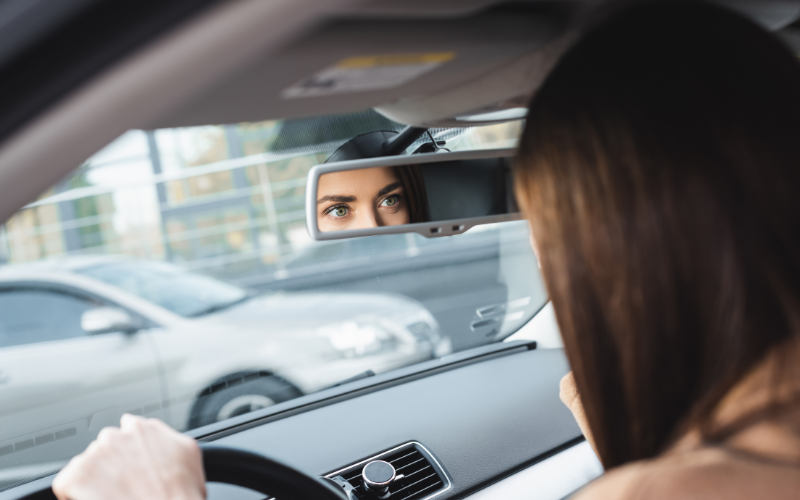 Woman focused while driving looking into interior mirror